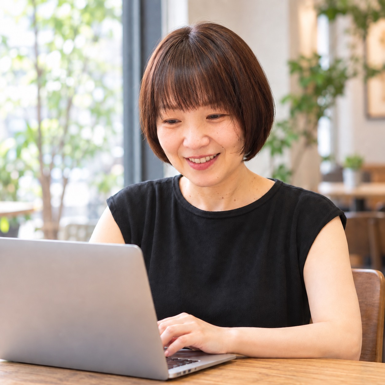 窓辺でパソコンに向かう、きどさおり